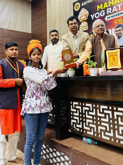 A student receiving her award at the Maharishi Patanjali Yog Ratna Sammaan, a prestigious event.