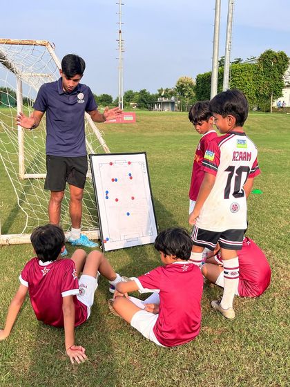 Learning the game on and off the ball. A coach details a play for our junior squad, ensuring every player understands their role within the team's structure.