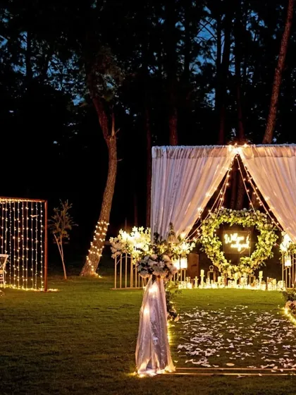 I love creating moments that feel like they're straight out of a fairytale. This outdoor proposal setup in Karjat combines the rustic charm of a forest with the elegance of fairy lights, a heart-shaped floral wreath, and a candlelit dinner for two. It’s a perfect example of how I blend natural beauty with personalized, romantic decor.