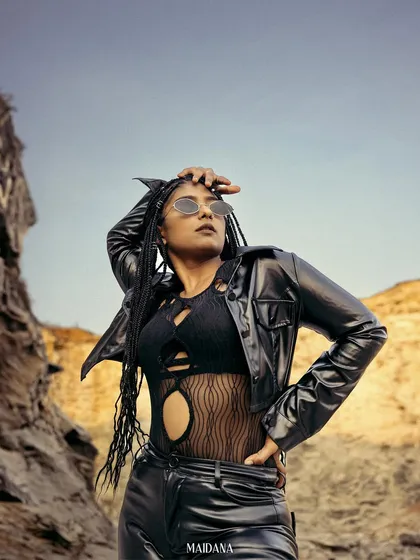This image captures a bold, edgy aesthetic for an outdoor fashion campaign. The model's strong pose in a black leather outfit against a rugged rock formation demonstrates our ability to create powerful, narrative-driven visuals on location.
