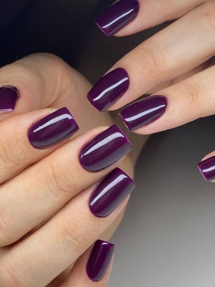 A deep, vampy purple polish on square-shaped nails. This rich, dark color is both sophisticated and bold.