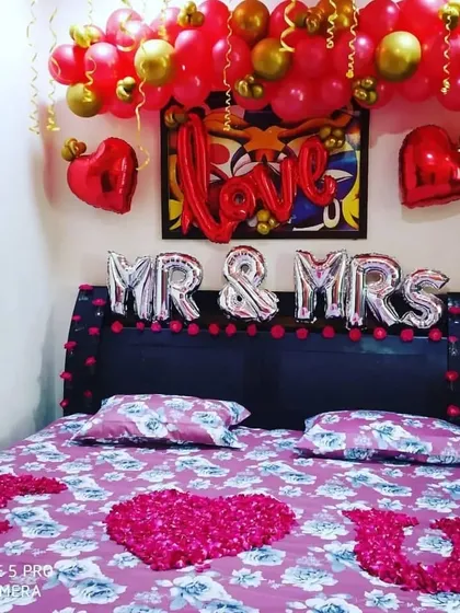 A "Mr & Mrs" room decoration for a newly married couple. The bed is decorated with rose petal hearts and "I love you", while the ceiling has red and gold balloons.