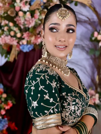 A close-up on the blouse and jewelry, showing the delicate floral embroidery on the green velvet fabric.