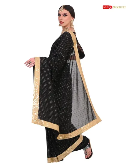 This image captures the elegant drape and flow of a black and gold saree. The model's pose is designed to highlight the fabric's movement, a key selling point for sarees online.