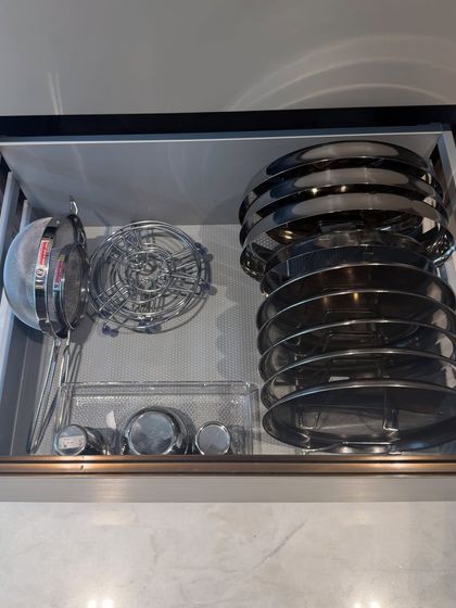 A drawer organized with various steel strainers, lids, and small bowls. We use a vertical rack to file the lids, which is a game-changer for kitchen organization.