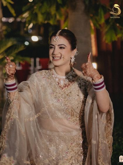 A happy bride giving a thumbs-up, her simple yet elegant white floral bun looking perfect.