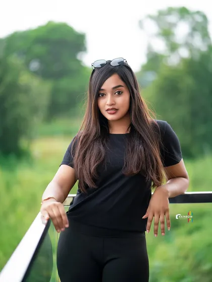 A relaxed portrait on a balcony, with the lush green background adding a natural and calming feel.