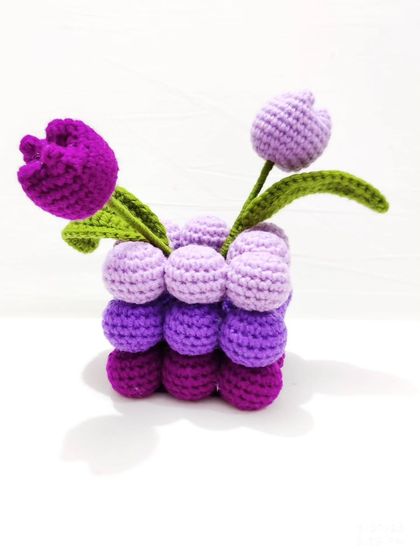 This adorable crochet tulip pot features shades of purple and is perfect for your workspace or any empty corner. The pot itself is made of soft, crocheted bobbles, adding a unique texture to the decor.