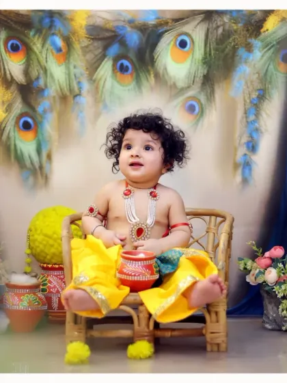 A complete view of our baby Krishna setup, featuring a wicker chair, peacock feather backdrop, and floral decorations for a rich, festive look.