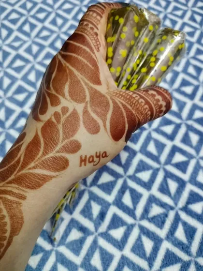 Holding my fresh, natural henna cones over a beautifully stained hand. This image shows the tools of my trade and the results they produce.