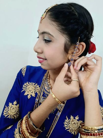 A candid moment as she puts on her earrings, showing a side profile of the simple hairstyle and makeup for her puberty ceremony.