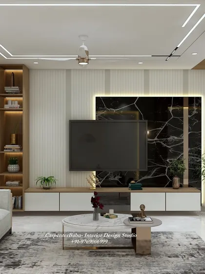 The TV unit in this tropical-themed home features a dramatic black marble panel, which contrasts beautifully with the light wood and white console.