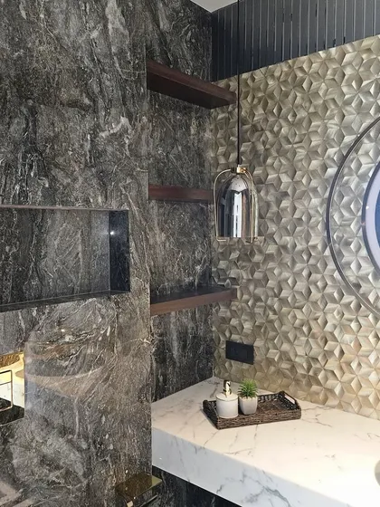 A powder room that embraces rich textures. The design combines dark marble with a 3D metallic tile accent wall, creating a sophisticated and tactile experience.