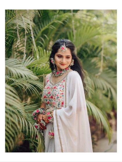 A lovely portrait of the bride in her traditional Haldi ceremony outfit. The focus is on her intricate floral jewelry and serene expression.