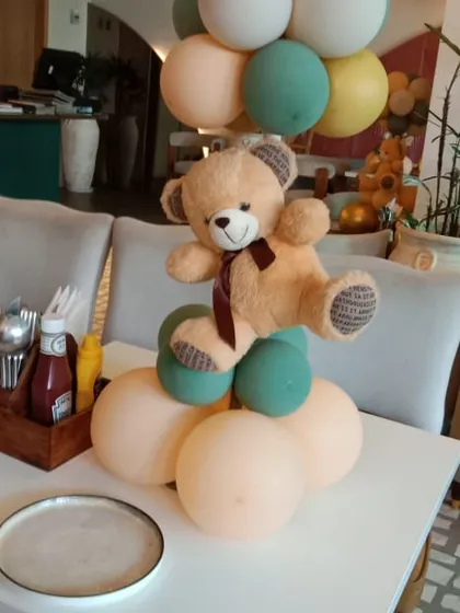 A simple yet charming teddy bear balloon centerpiece. This can be placed on tables or as a standalone decoration, featuring a cute teddy bear appearing to float with a bunch of pastel balloons.