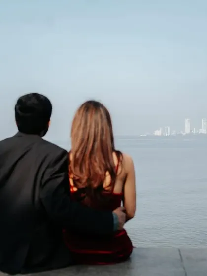The couple enjoying a quiet moment together, looking out at the sea with the iconic Mumbai skyline as their backdrop.