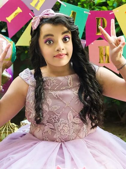 The birthday girl flashes peace signs, full of personality and fun during her colorful outdoor party.