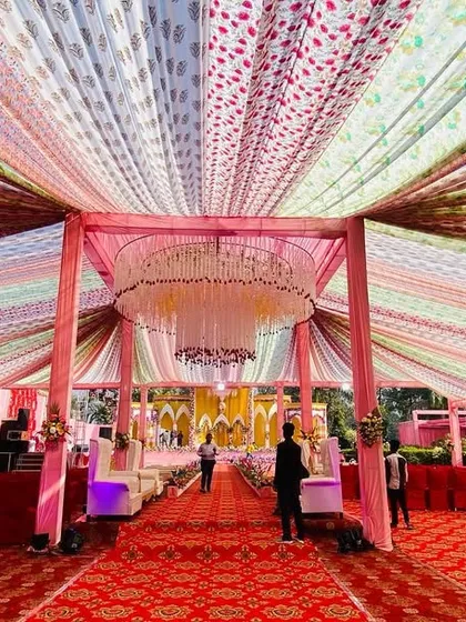 A stunning wide-angle shot of a large tent with a ceiling covered in colorful patterned fabric strips, all leading to a massive floral chandelier.