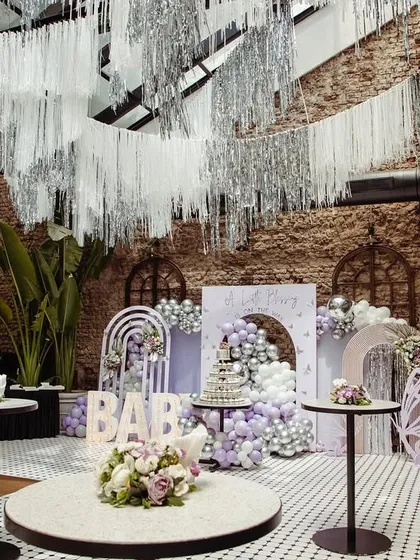 An overall view of the venue, showing how we used ceiling tassels, balloon pillars, and multiple decor elements to create an immersive lavender wonderland.