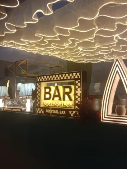 An elegant bar setup with a unique lit canopy. The custom 'BAR' sign and art-deco style decor elements create a sophisticated and memorable look.