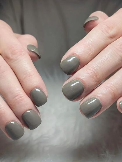 A chic and understated manicure featuring a solid olive-grey polish on short, neatly shaped nails.