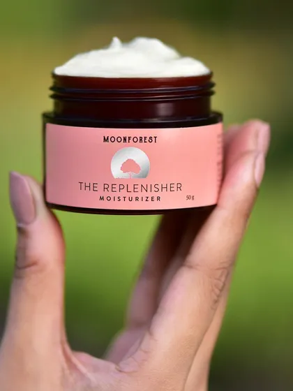 A hand-held shot of Moon Forest's moisturizer, showing the creamy texture of the product. This personal, close-up view is relatable and effective for social media.
