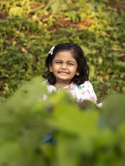A cheeky smile while peeking through the leaves. These playful moments are what make milestone sessions so much fun, capturing the true personality of your child.