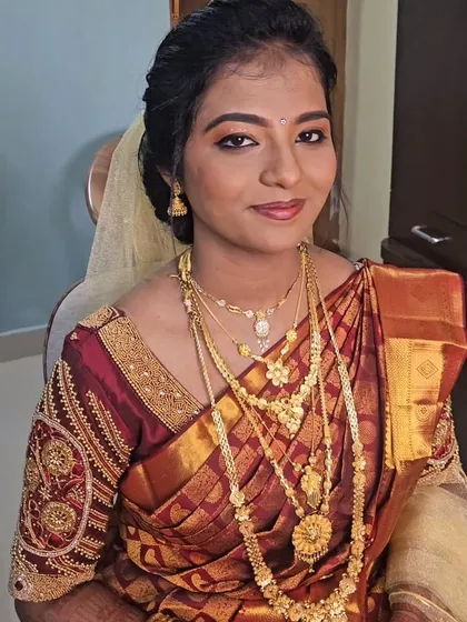 A Christian wedding look featuring a traditional maroon saree. The makeup is soft and glowing, complementing the rich color of the saree.