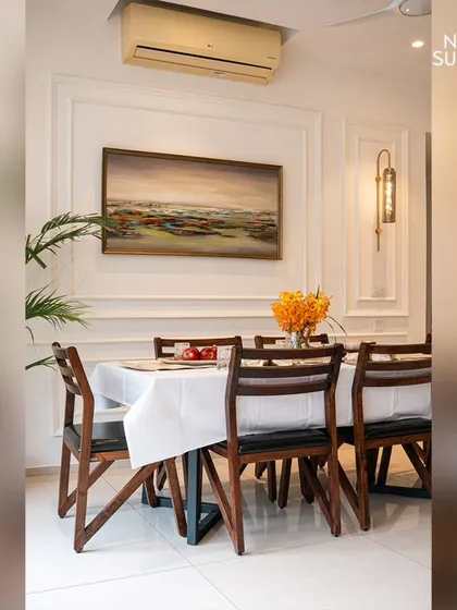 A focused view of the dining table and chairs, emphasizing the clean lines of the furniture against the detailed wall treatment. The design proves that elegance lies in the careful balance of simplicity and ornamentation.