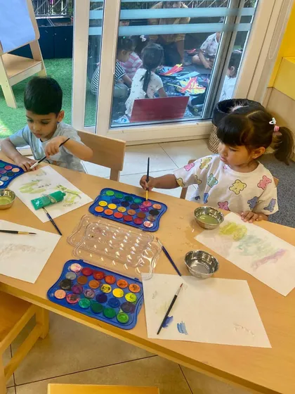 Working side-by-side, these children are engaged in a quiet, focused watercolor session. While their work is individual, the shared space fosters a sense of community and parallel learning.