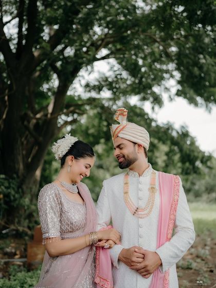 A sweet moment shared under the trees. Dressed in elegant wedding attire, this shot is perfect for a pre-wedding album, capturing a quiet and happy connection.
