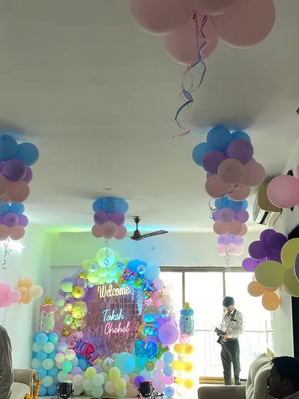 A wide view of the room decorated for the twins' welcome party, showing ceiling balloons and the main backdrop.