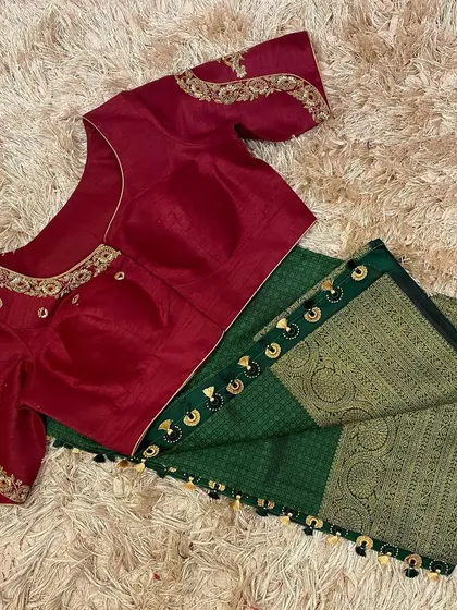 A rich maroon hand-embroidered blouse paired with a deep green silk saree, finished with beautiful custom tassels.