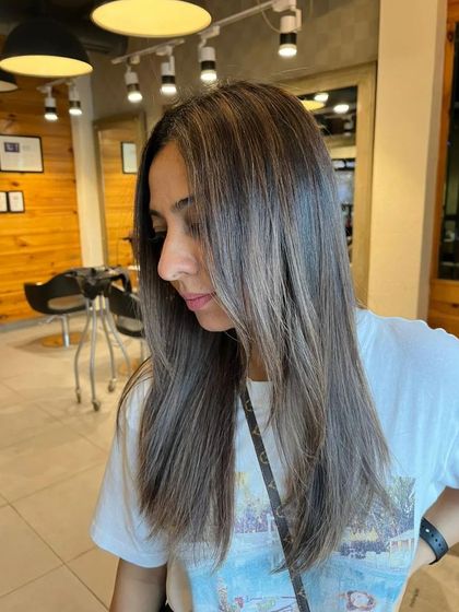 A side profile of a client's new color on straight hair, showing the delicate layers and face-framing color.