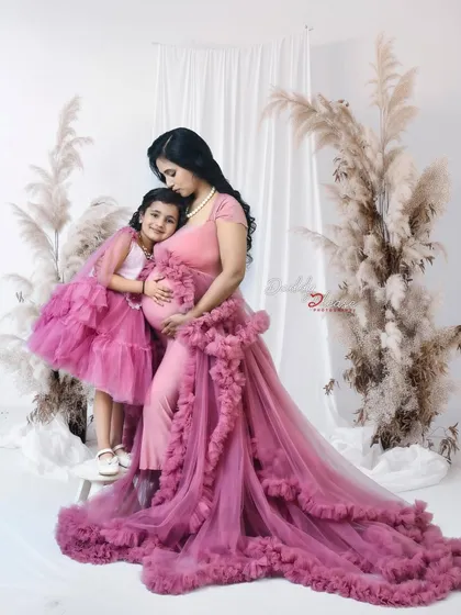 A tender moment between a mother and her daughter during a maternity session. The daughter hugs her mother's baby bump, showing her love for the new sibling on the way.