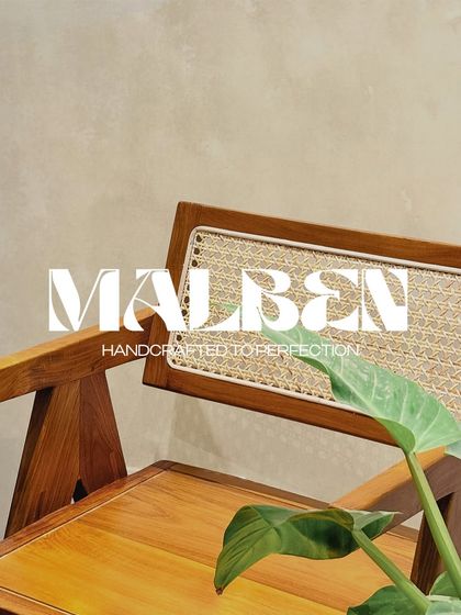 A close-up of the 'Malben' chair, showcasing its clean lines and the contrast between the solid teak frame and the airy rattan backrest. Handcrafted to perfection.