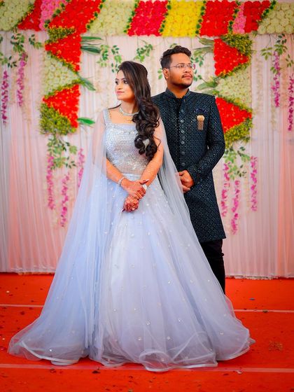 A couple posing for a portrait at their ring ceremony, in front of the stage decor.