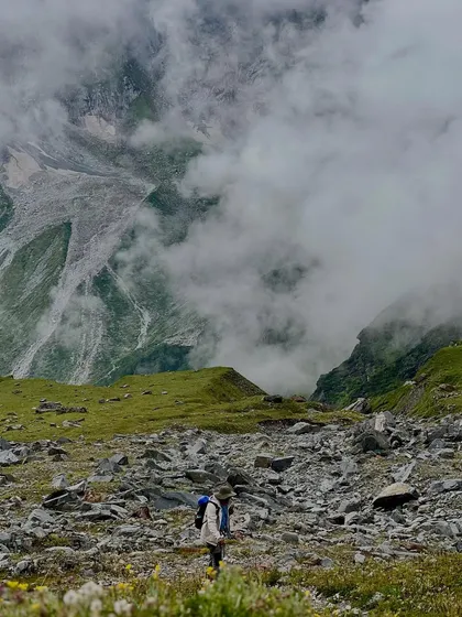 A trekker walking through a misty, rocky valley on the Friendship Peak trail. The atmosphere is raw and powerful.