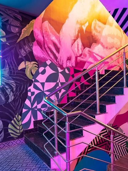 The entrance to the 'Highdrate' staircase, where neon lights and bold, colorful murals welcome guests. The design immediately signals a fun and vibrant experience ahead.