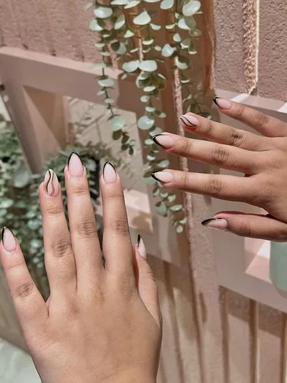 A minimalist and modern take on the French manicure, featuring a thin black tip and an abstract swirl accent nail.