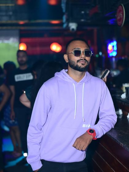 A candid-style shot, leaning against the bar. This captures my relaxed but confident personality in the club environment.
