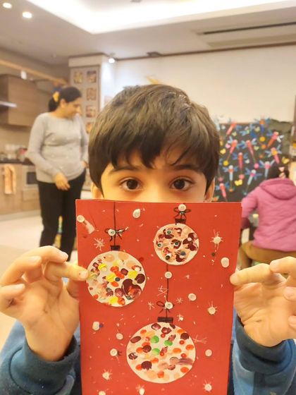 Peeking over his handmade Christmas card! This project was a hit with my 3 to 6-year-old group, who loved creating the textured, colorful ornaments.