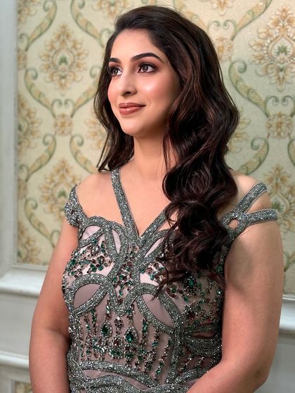 A side view of this elegant look, showing the soft waves in her hair and the flawless, radiant finish of the makeup.