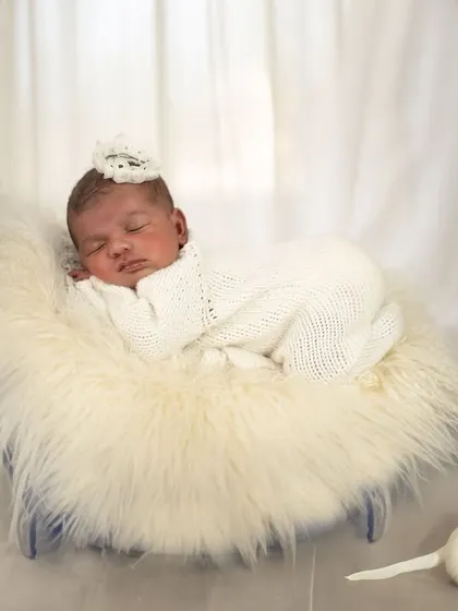 In the calm of her slumber, we see the magic of pure peace. This angelic shot features a baby sleeping on a fluffy fur-lined crescent moon prop, with a tiny puppy figure nearby.