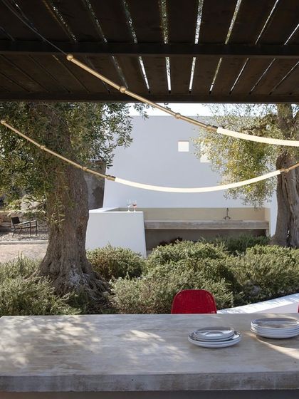 The Leda system provides architectural lighting under a modern pergola, its linear form complementing the structure and illuminating the outdoor dining area.