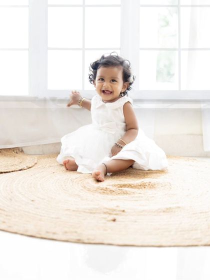 A solo portrait of the adorable baby girl from the family session, smiling happily.