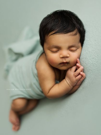 The perfect womb-like curl. This pose shows how flexible and tiny newborns are in their first few weeks. The soft lighting highlights the beautiful contours of the baby's body.