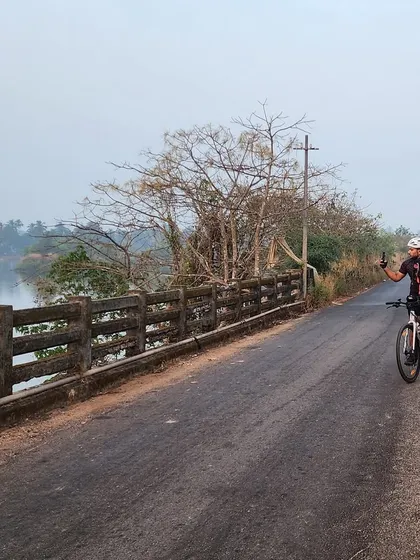 A rider enjoying the view from a bridge over the backwaters. Our routes are a mix of coastal roads and serene riverside paths.
