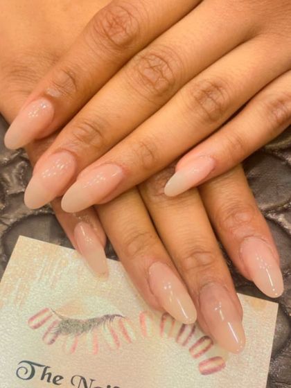 A beautiful set of long, almond-shaped extensions in a sheer, natural-looking nude. This is a perfect example of a simple, elegant, and timeless nail style.