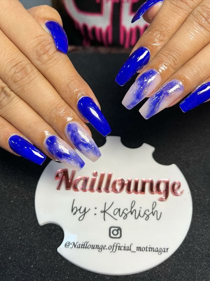 A striking royal blue set with accent nails featuring a beautiful blue and white marble effect.
